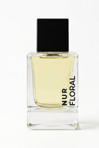 A rectangular glass perfume bottle filled with pale yellow liquid, featuring a matte black cap and vertical black text reading 'NUR FLORAL' on the front, set against a plain white background.