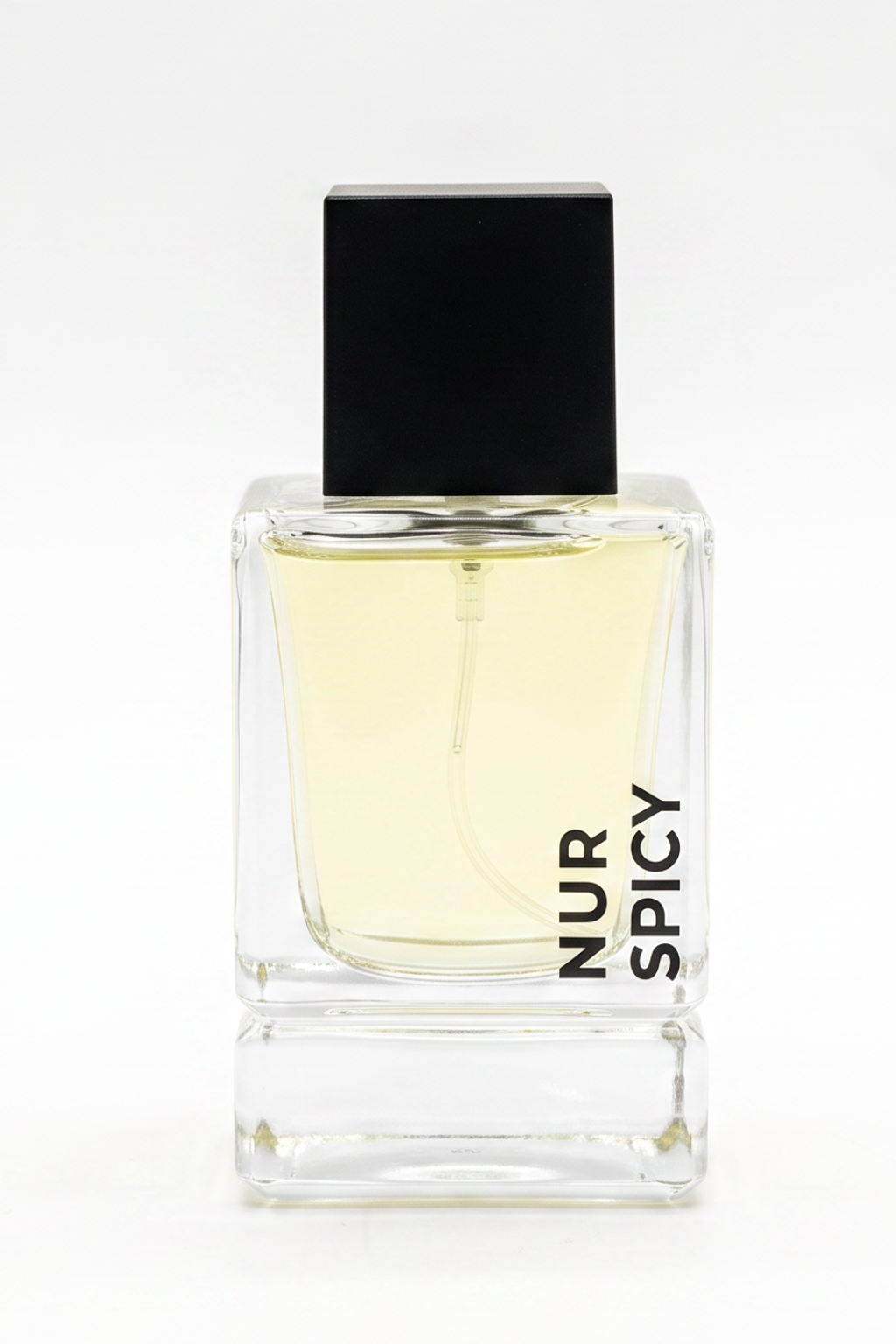 A clear glass perfume bottle with pale yellow liquid, a black rectangular cap, and vertical black text reading 'NUR SPICY' on the front, shown on a white background.